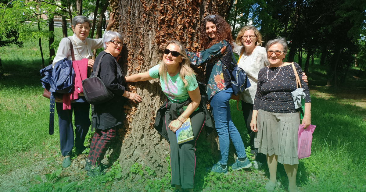 gruppo di persone abbracciate attorno ad un albero