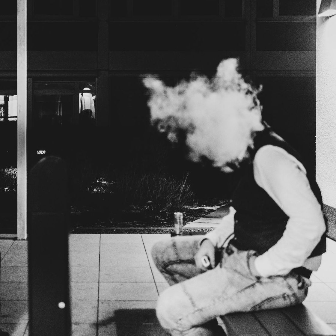 Mann sitzt, sein Kopf ist verdeckt mit Rauch.