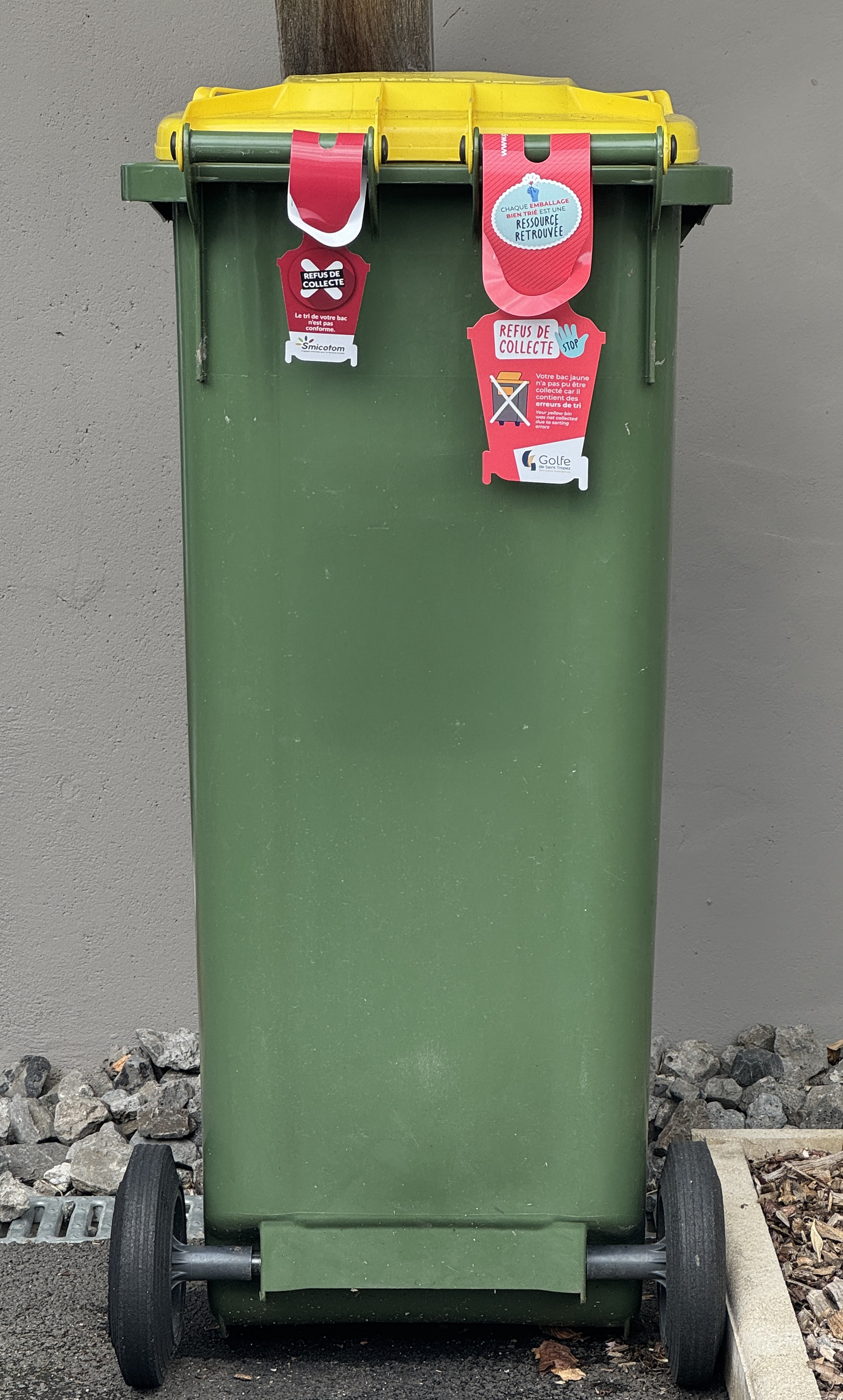 Étiquette rouge de refus de collecte accrochée sur un bac jaune de tri sélectif