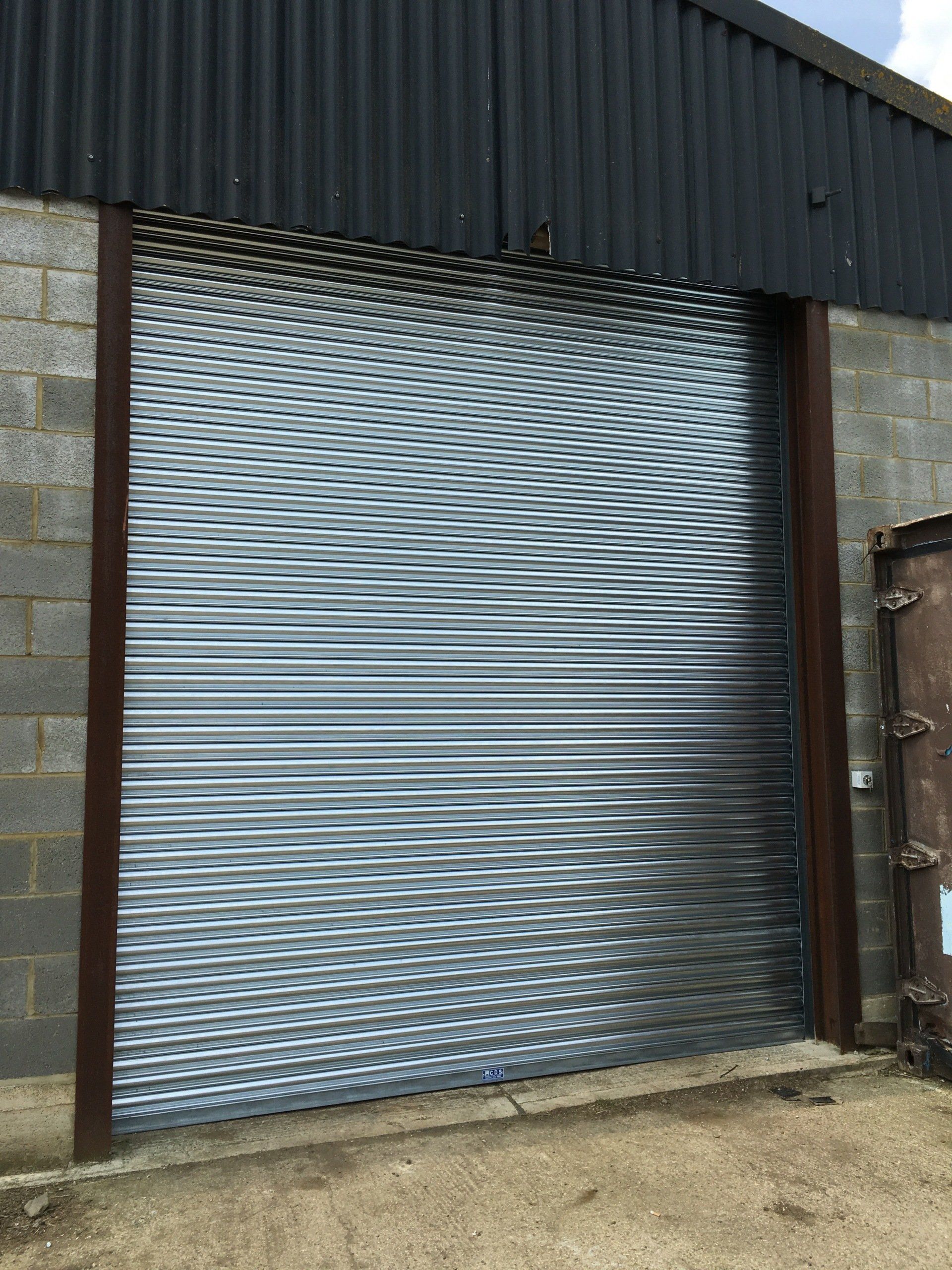 Silver roller shutter on brick and metal unit