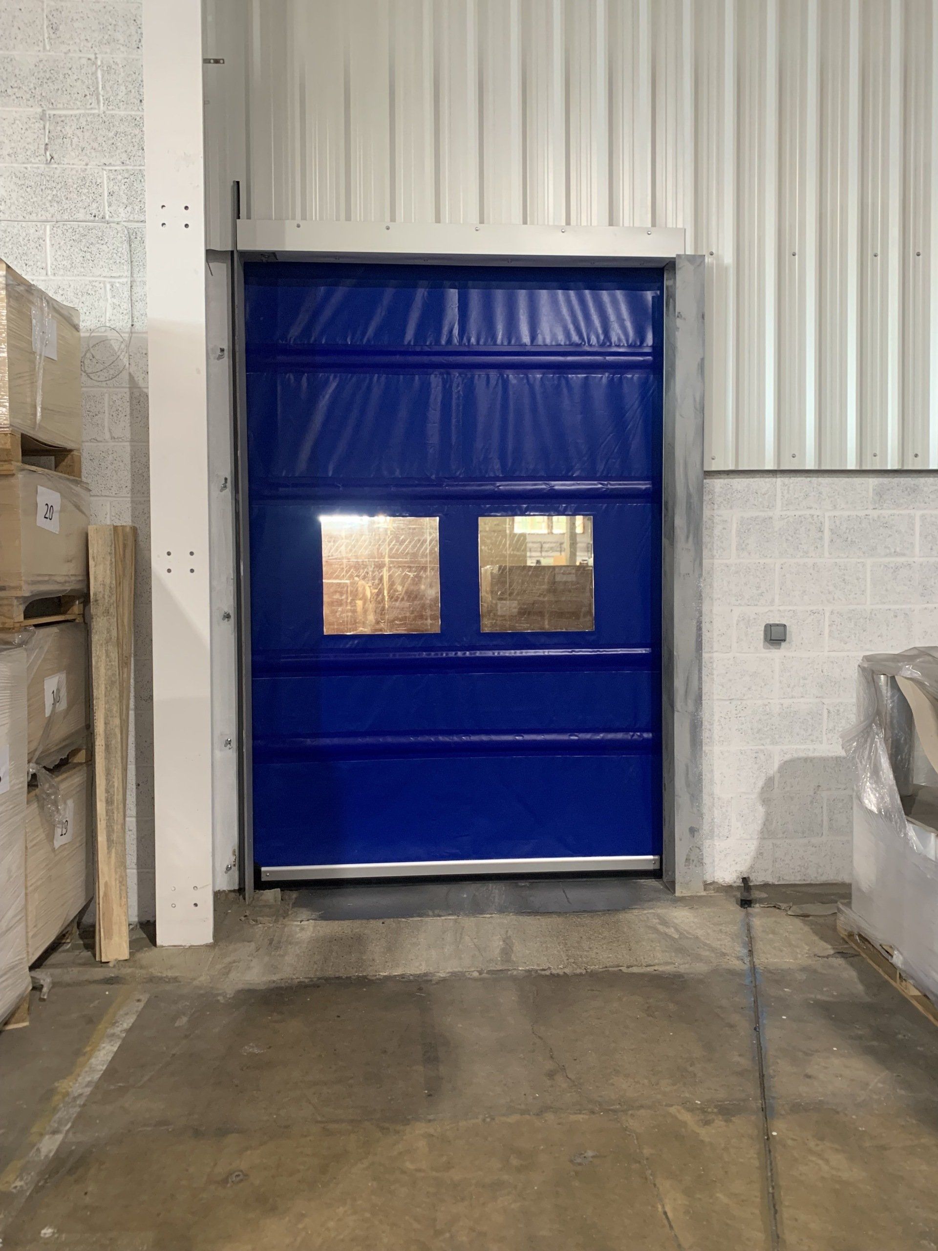 Blue high speed rapid roll door with twin vision windows in factory setting