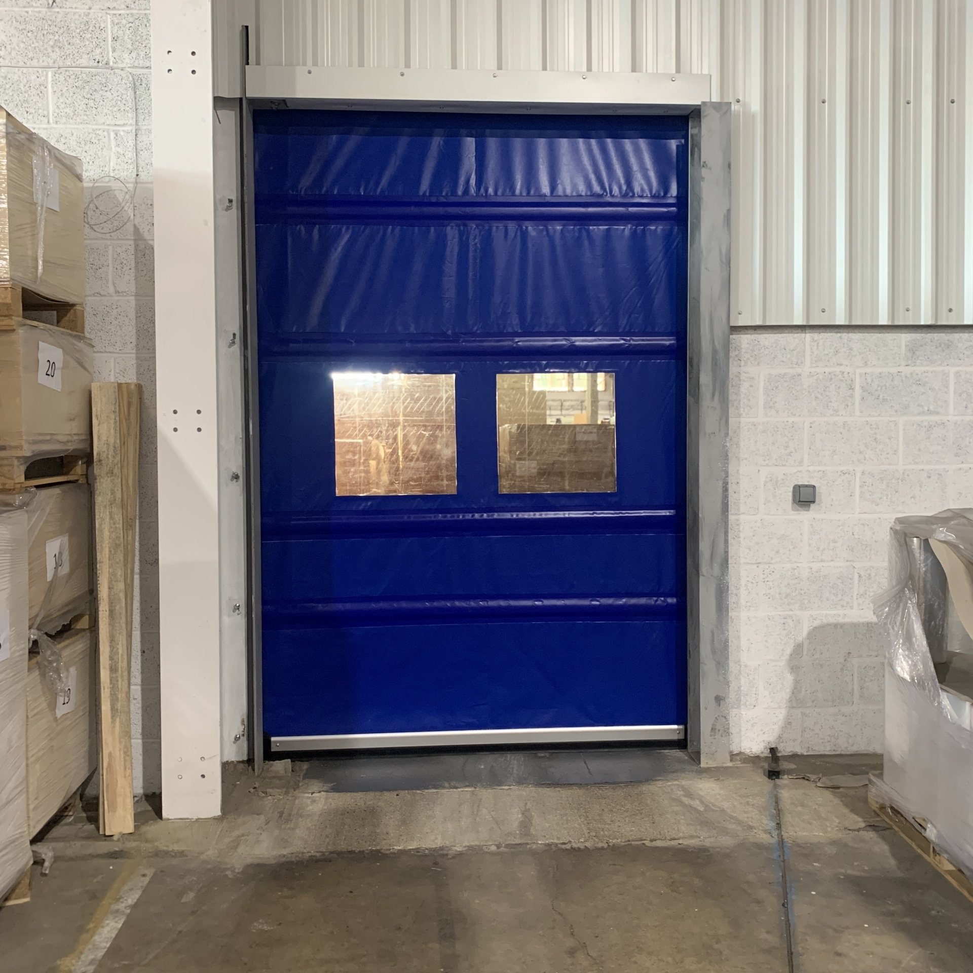 Blue high speed rapid roll door with vision panels inside warehouse