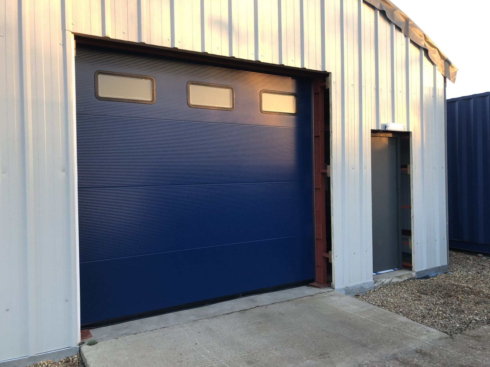 Blue sectional industrial door with vision panels on warehouse exterior