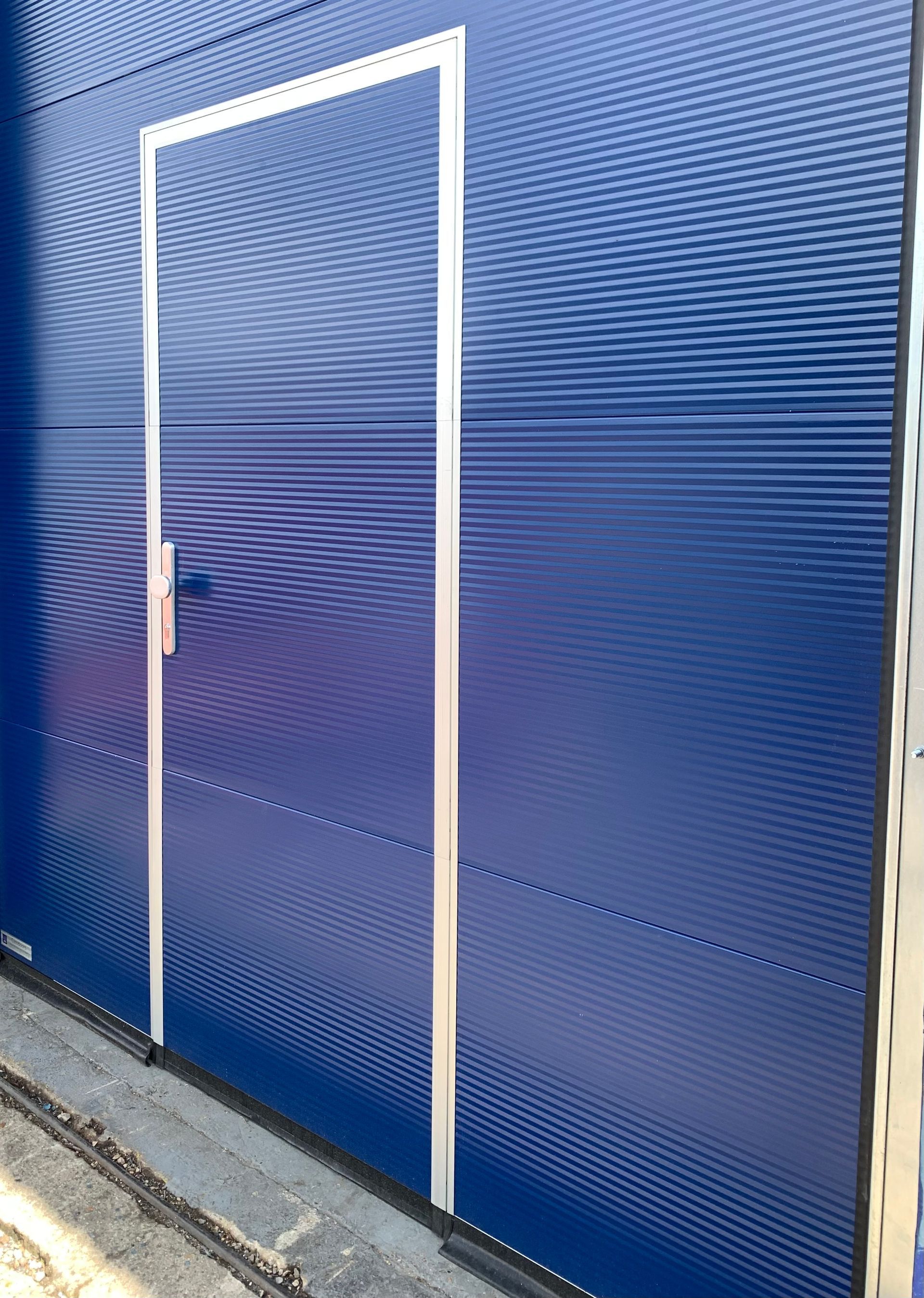 Blue sectional door with integrated pedestrian door