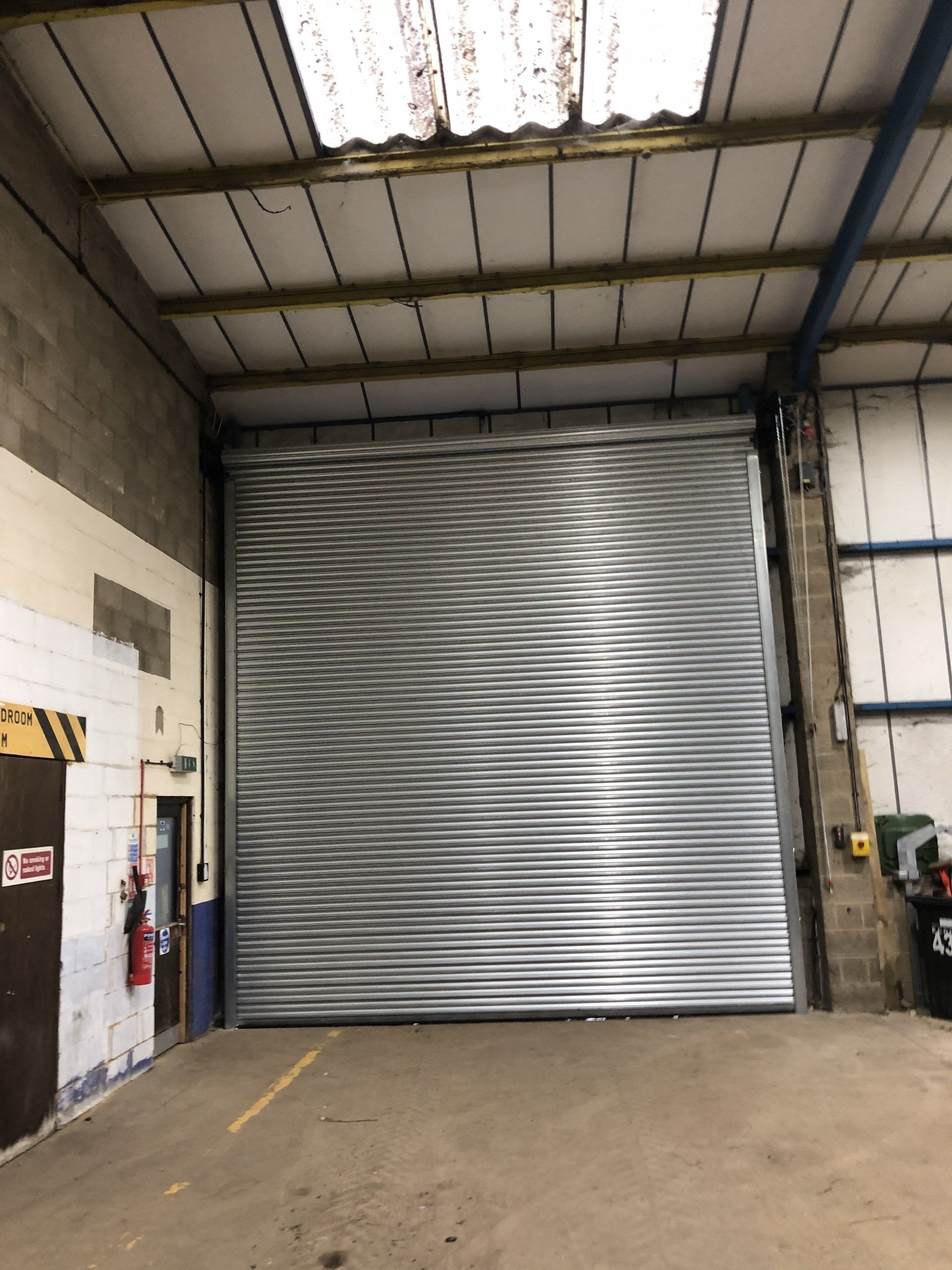 Large silver roller shutter door viewed from inside a warehouse
