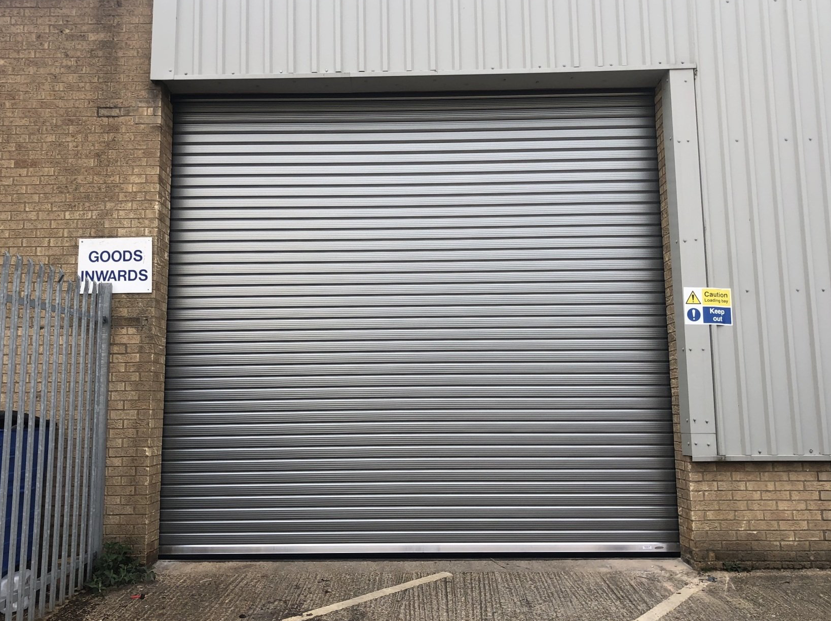 Silver roller shutter door with goods inwards sign