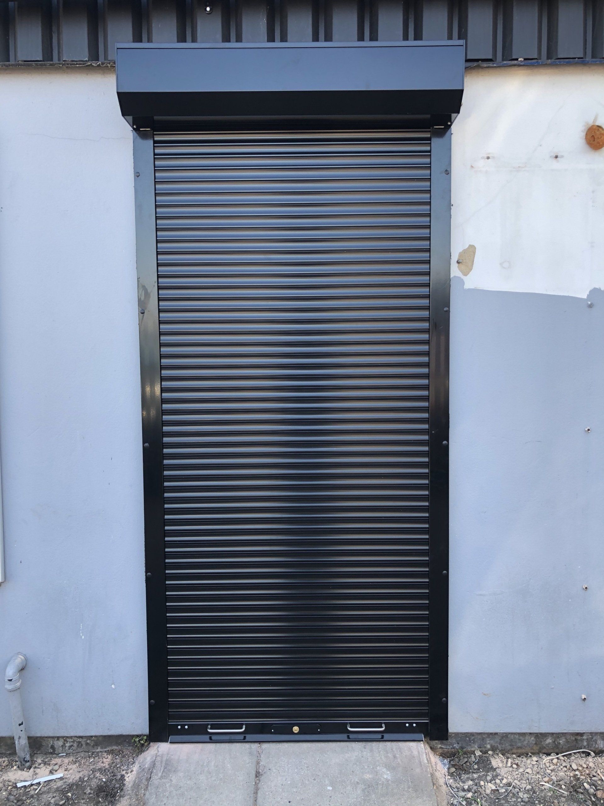 Black roller shutter door installed on a commercial unit entrance