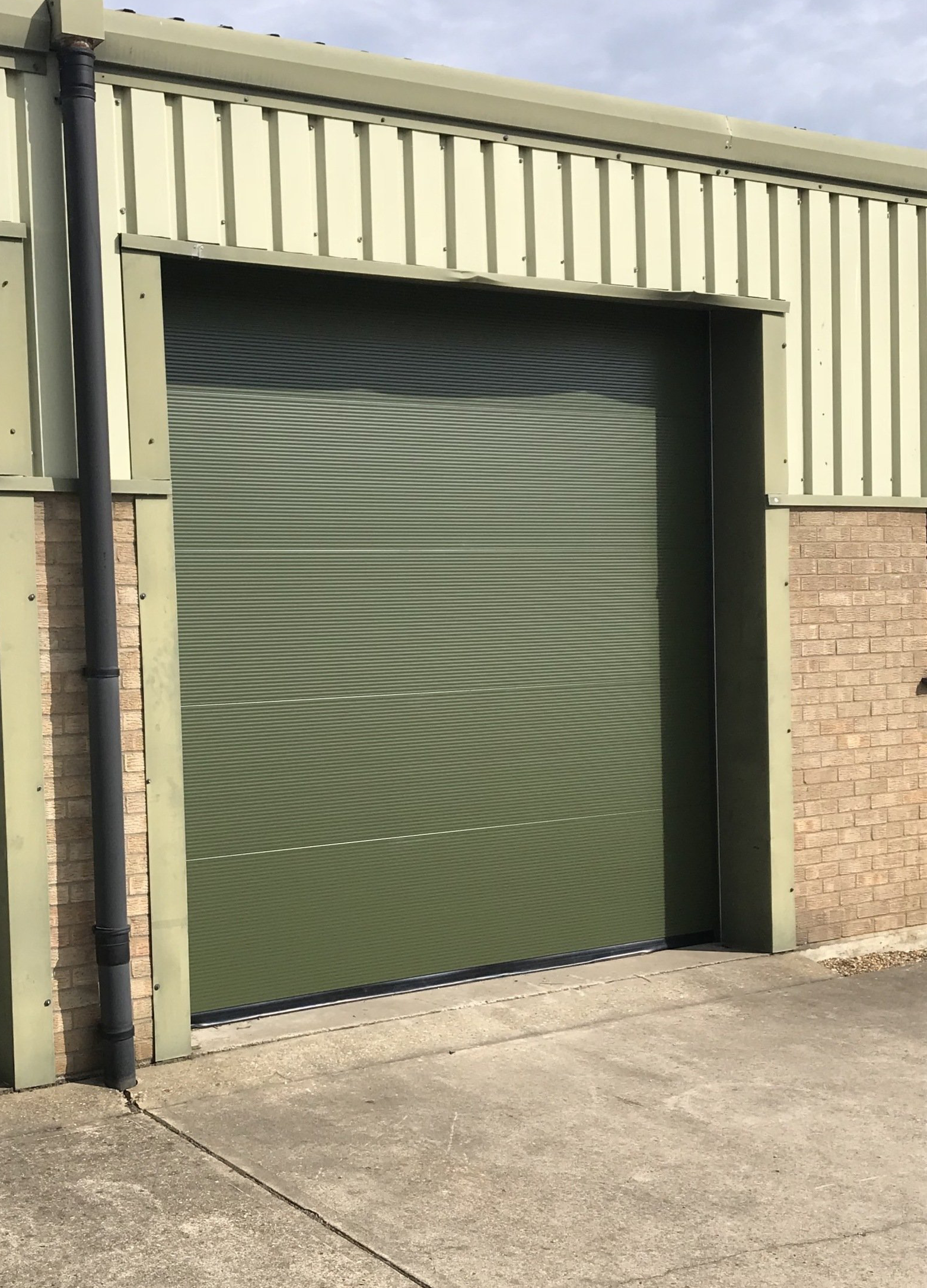 Green sectional overhead door installed on industrial unit