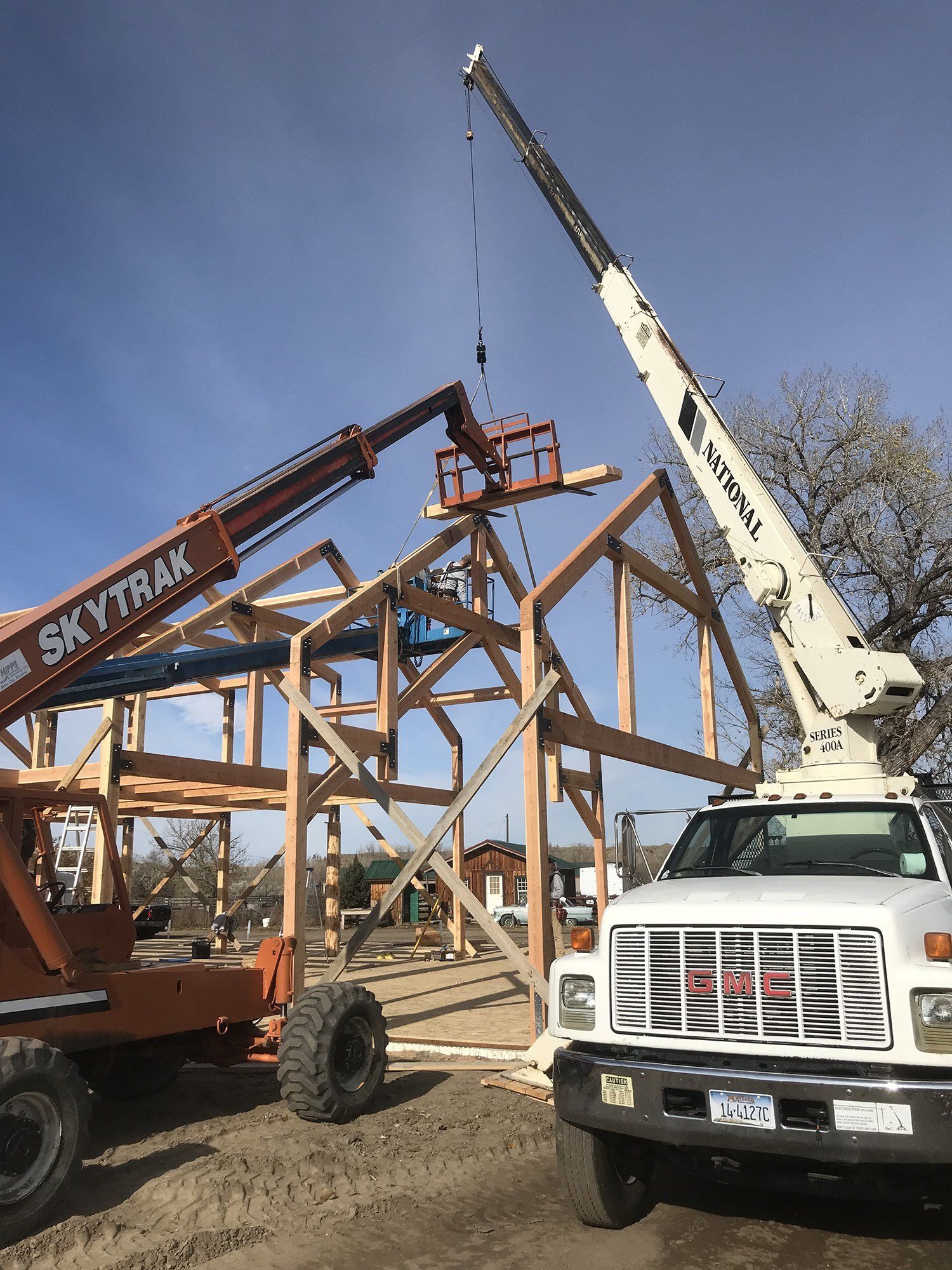 crane lowering posts onto a wooden frame house
