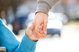 Picture of one hand holding the hand of person in a wheelchair symbolising support