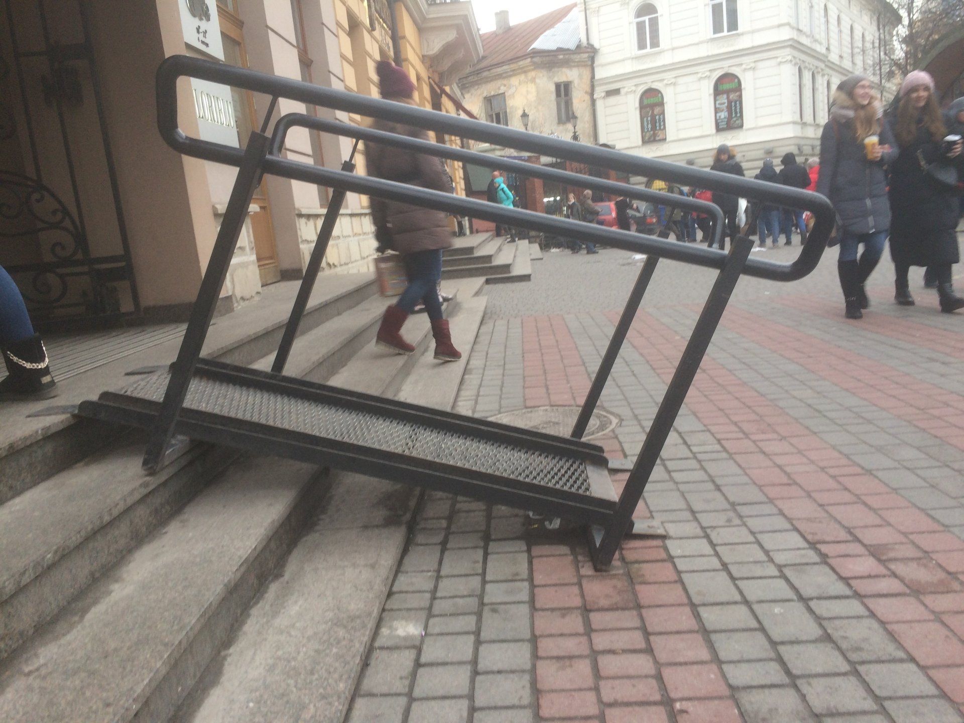 Picture of very steep shot metal ramp with very high handrails going up five steps into supermarket.