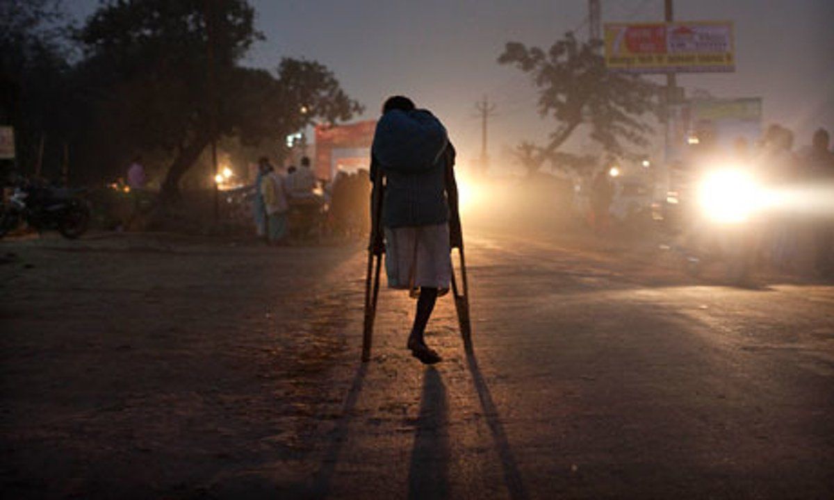 Picture showing the back of an older at night time with lights glimmering on crutches