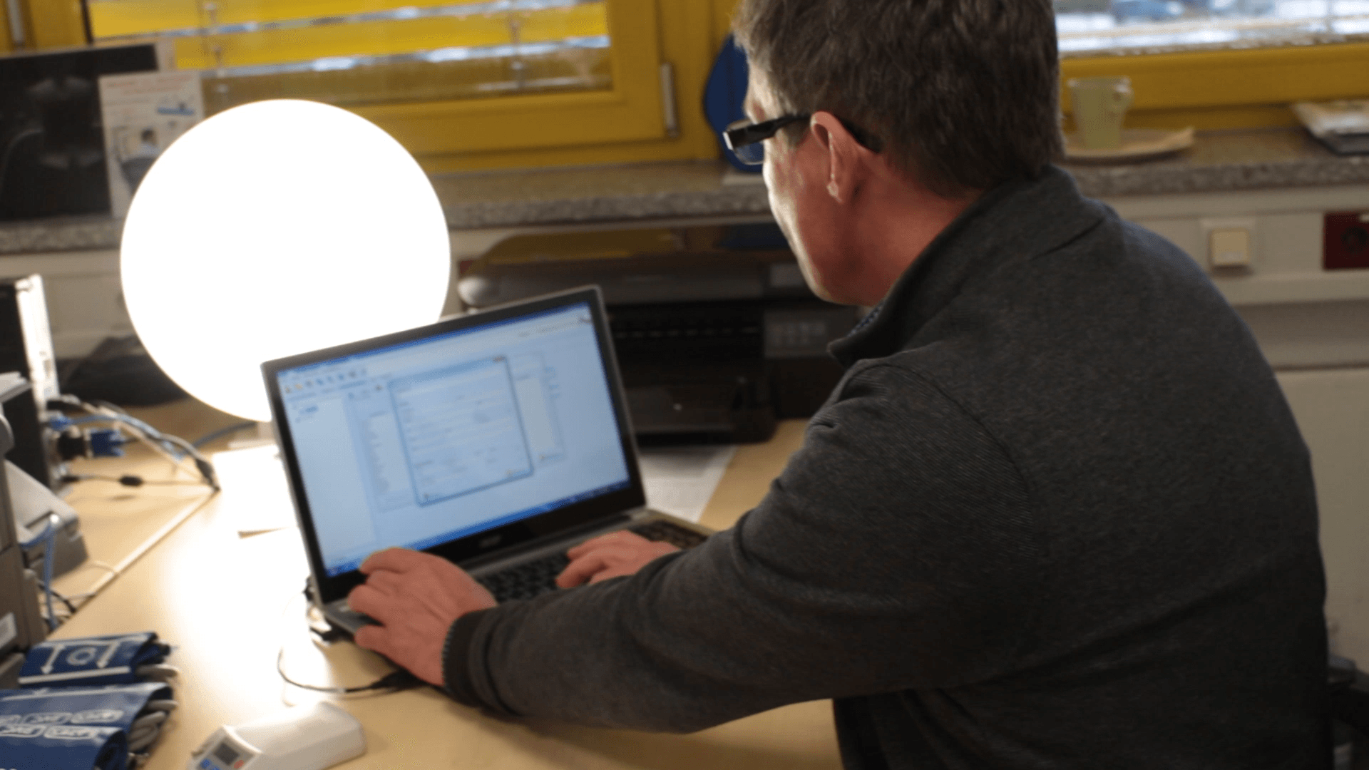 Ein Bild, Mann arbeitet am Laptop, Lichttherapiegerät