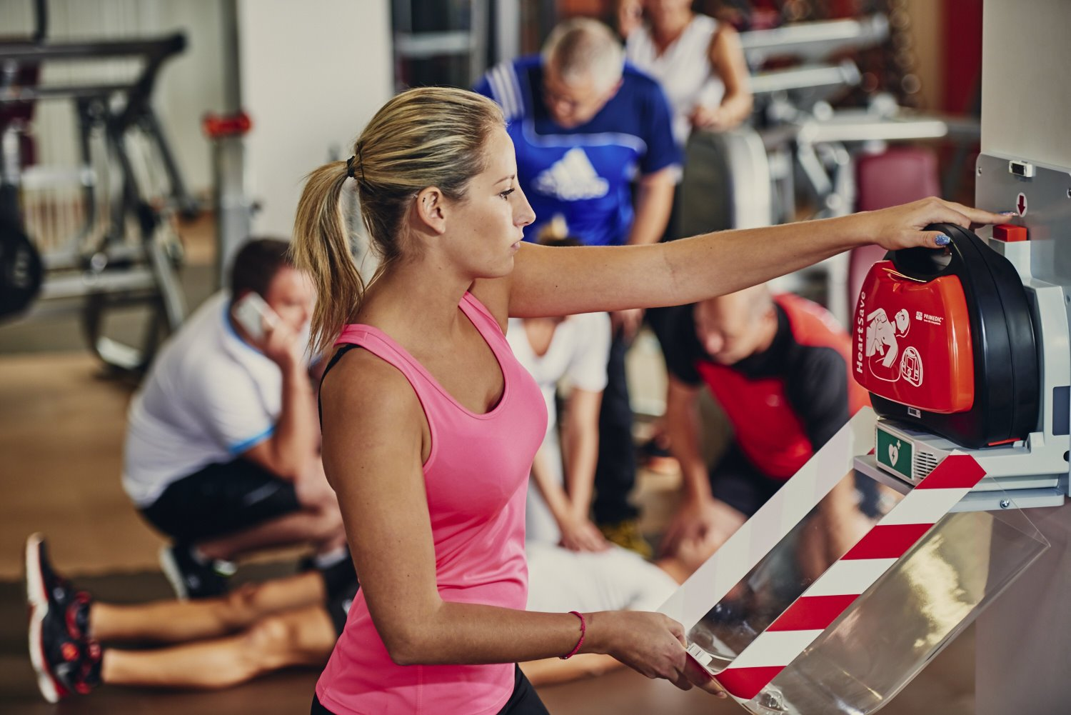 junge Frau holt Defibrillator im Fitnessstudio