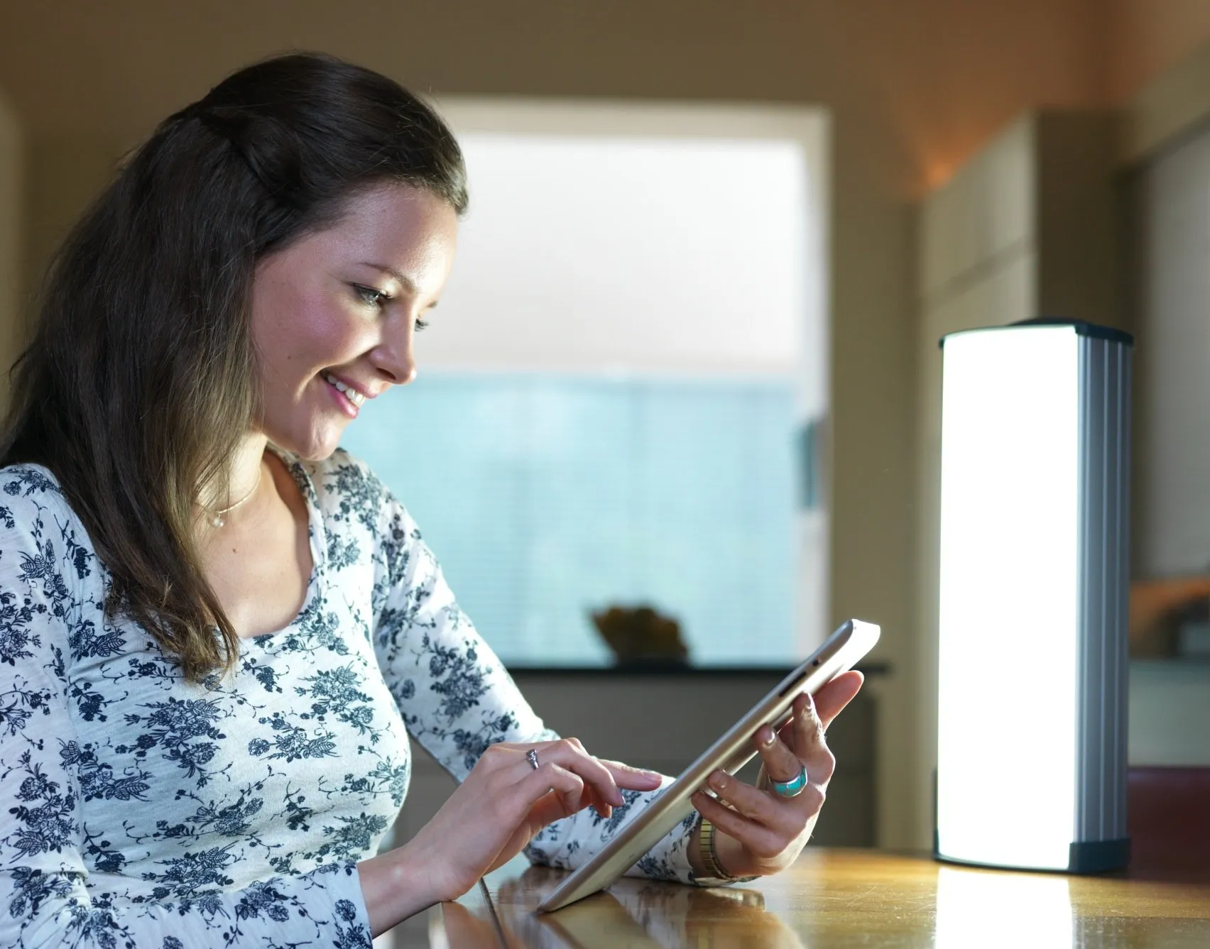 ein Bild, Frau mit Tablet, Lichttherapiegerät auf dem Tisch