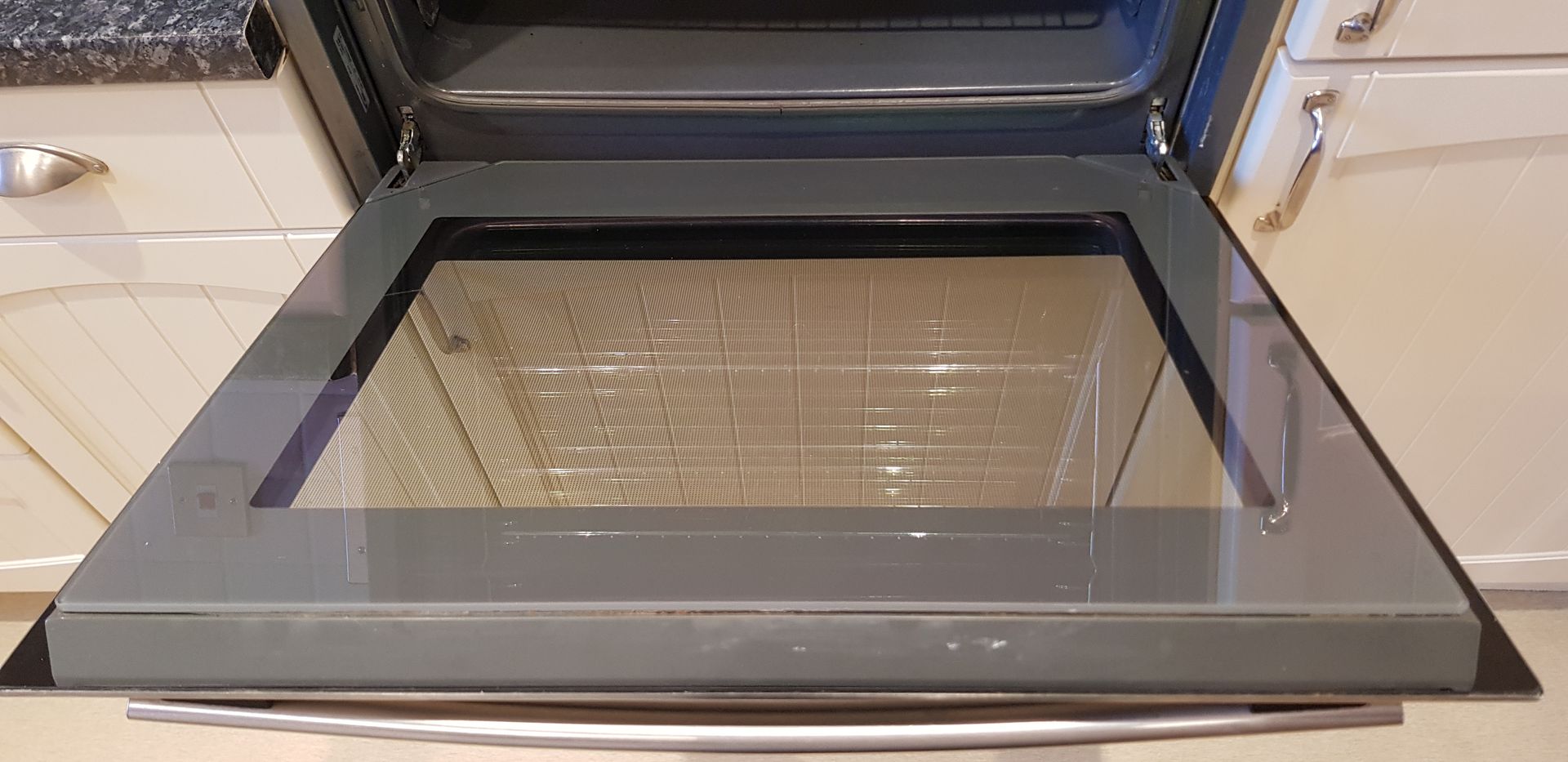 A spotless black oven with a gleaming glass door and top, showcasing its sleek design. Fresh from an expert oven cleaning, it shines with efficiency and is ready for use."