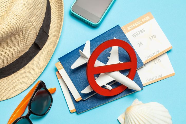 Avión en miniatura con señal de prohibido encima de dos pasaportes