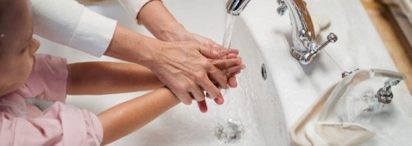 Madre ayudando a su hija a lavarse las manos