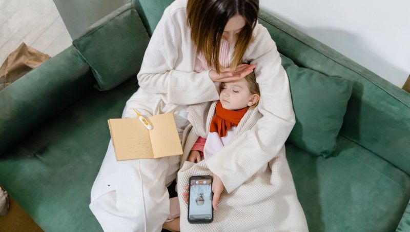 Madre comprobando la fiebre de su hija
