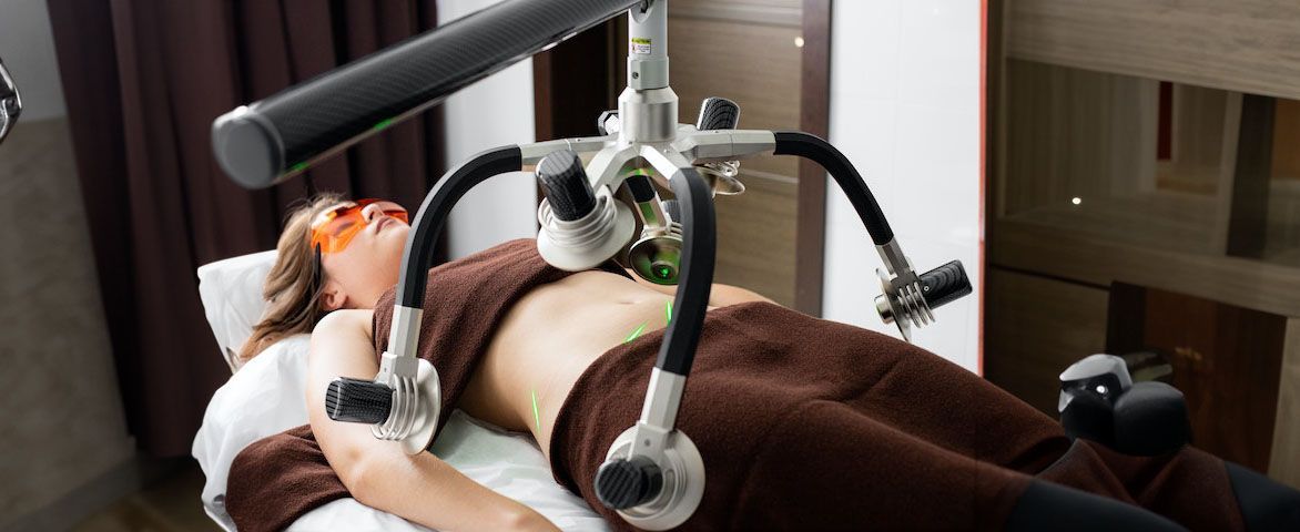 Mujer tumbada en una camilla sometiéndose a una prueba médica láser en su abdomen