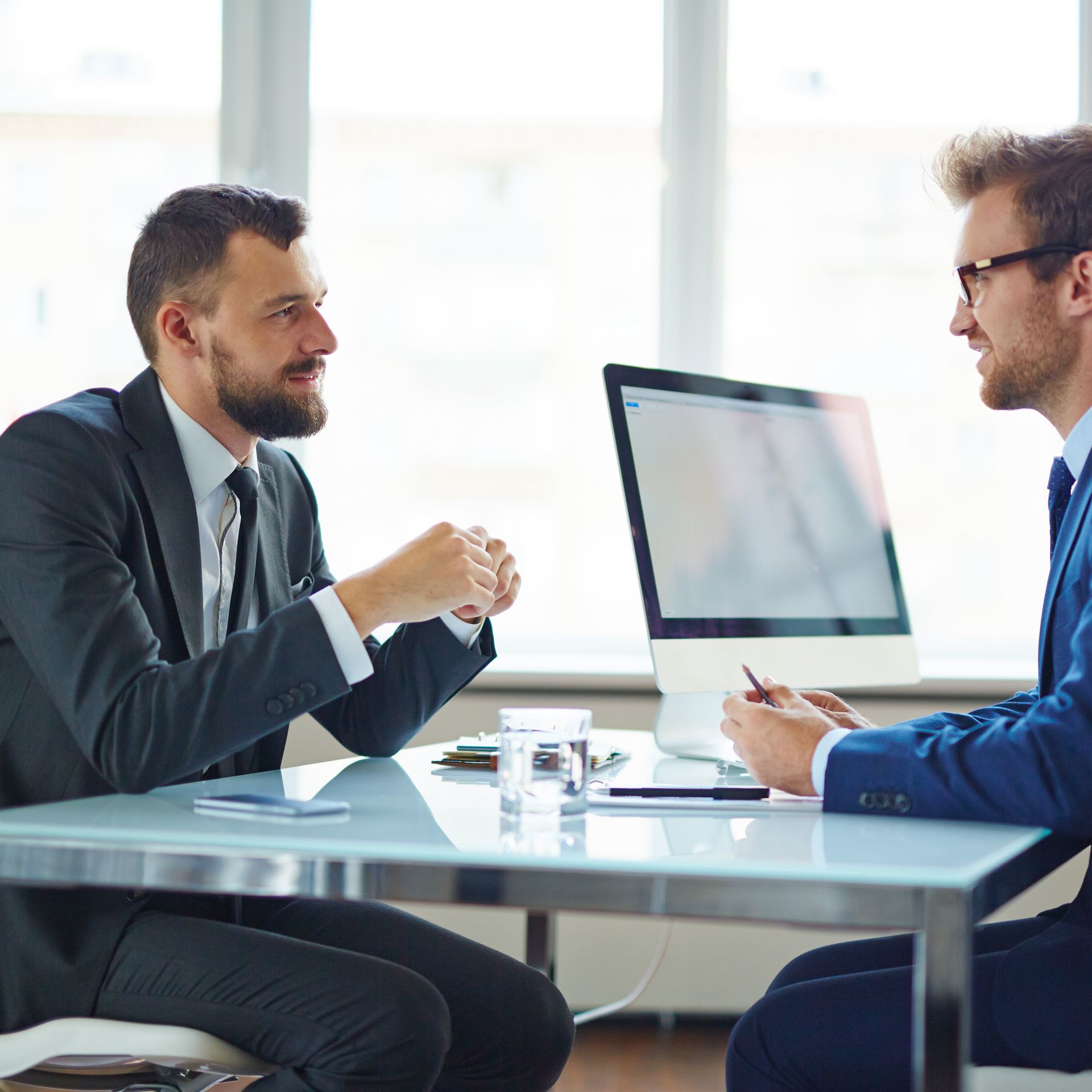 2 men talking across from each other at a desk