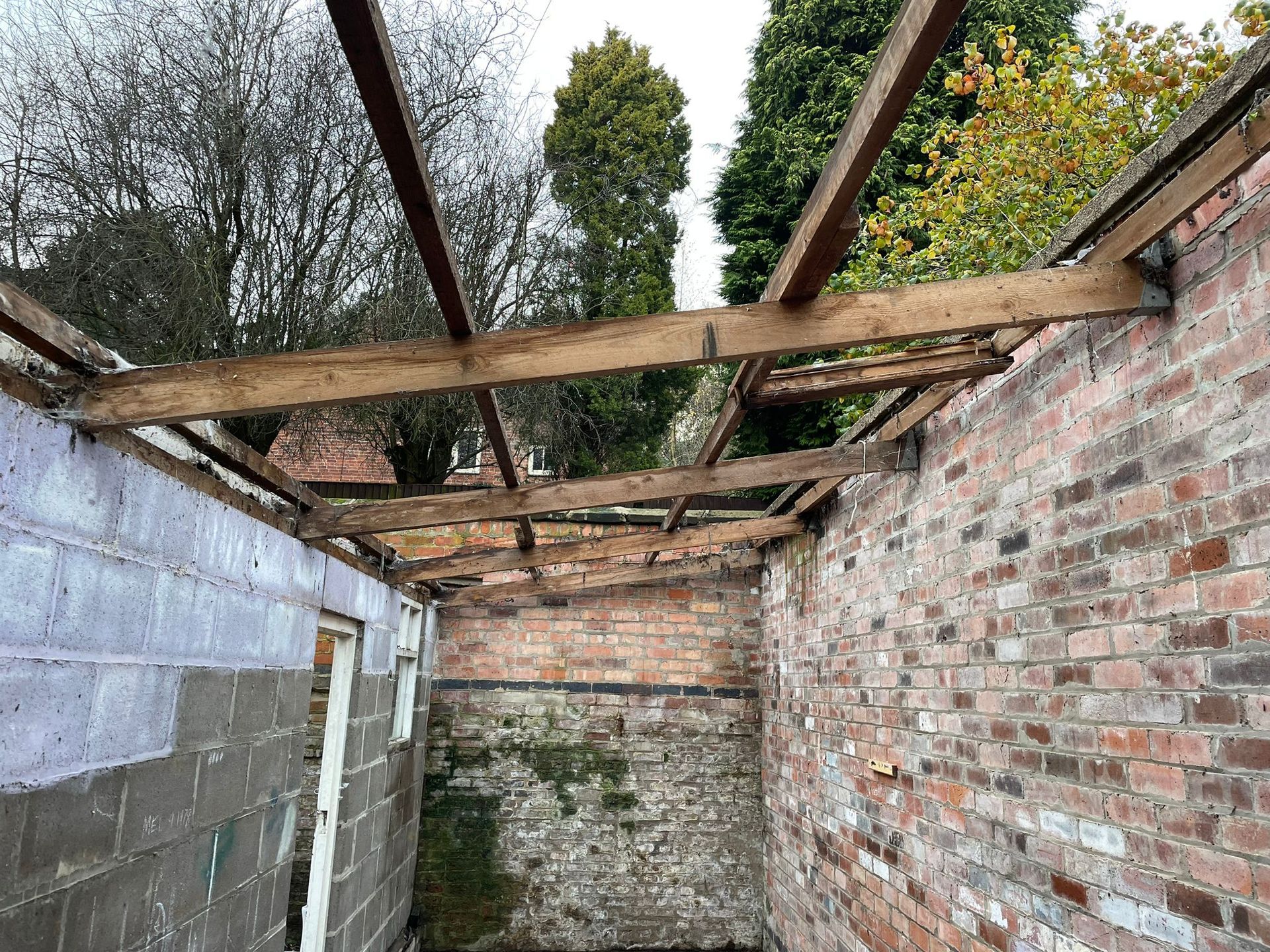 image showing removal of the asbestos cement roof sheets on a brick outbuilding with wooden joists