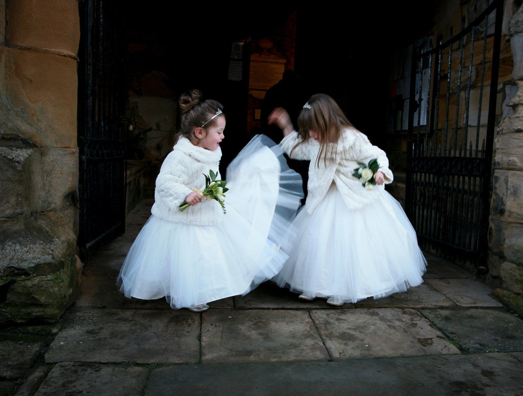 2 flowergirls waiting for the bride playing with their dresses