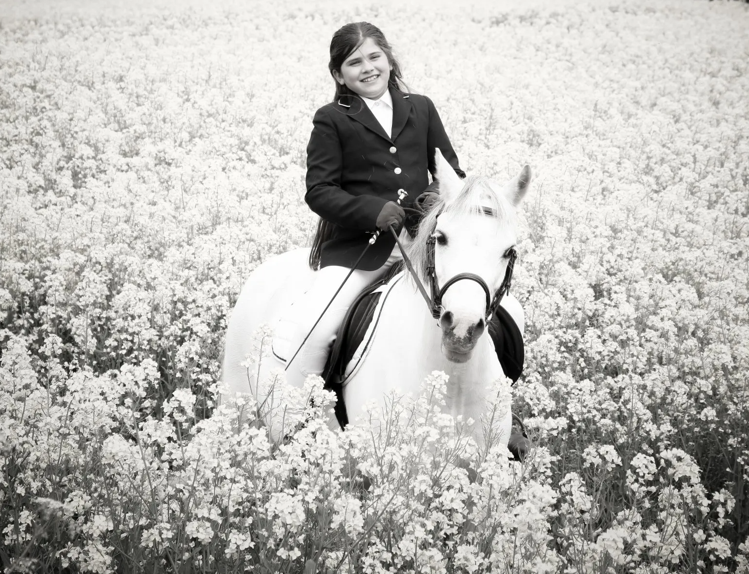 girl on her pony in a wild flower field both looking at the camer