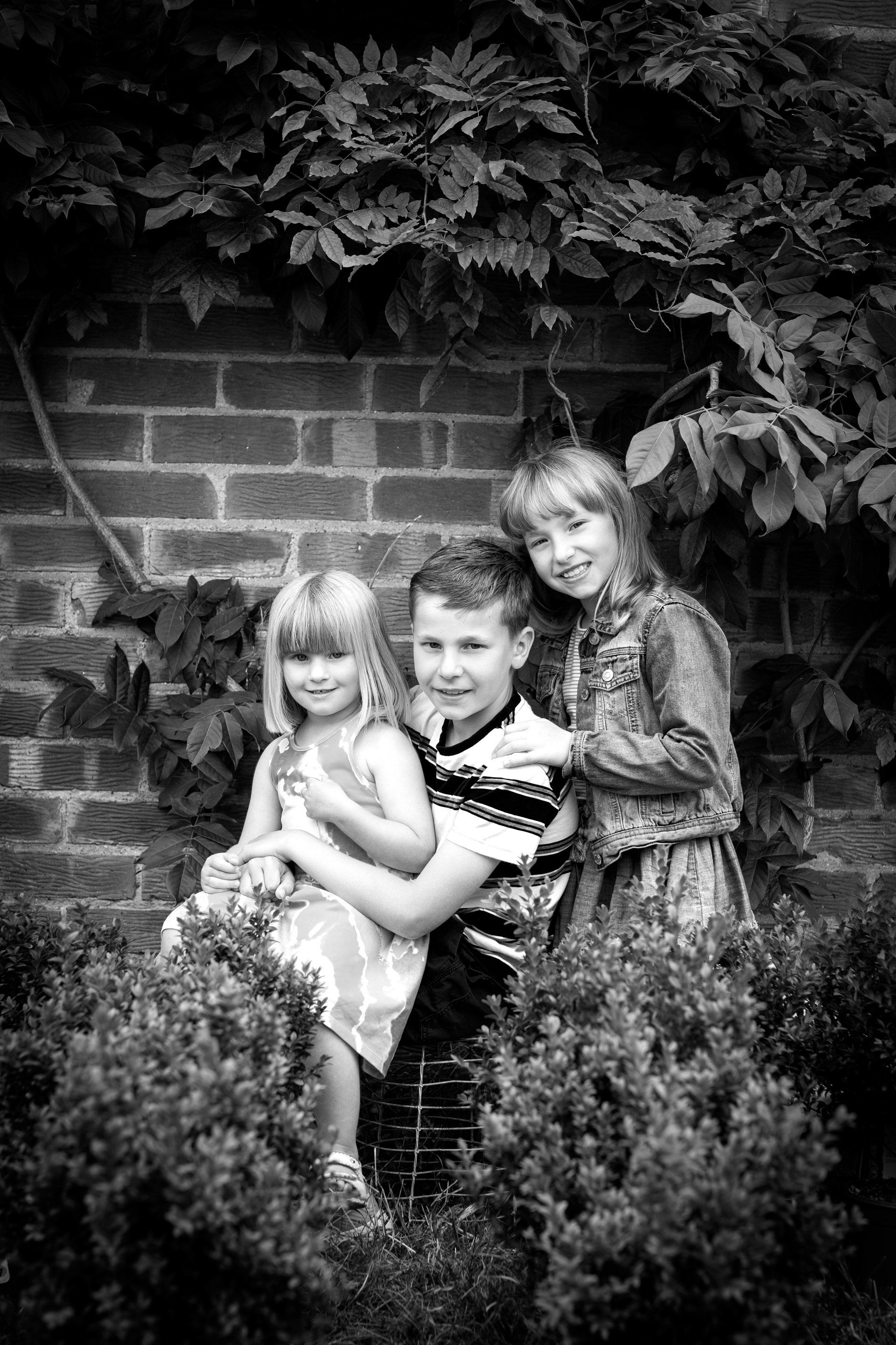 siblings sitting on a ladder looking at the camera, sitting close to each other and smiling in darlington