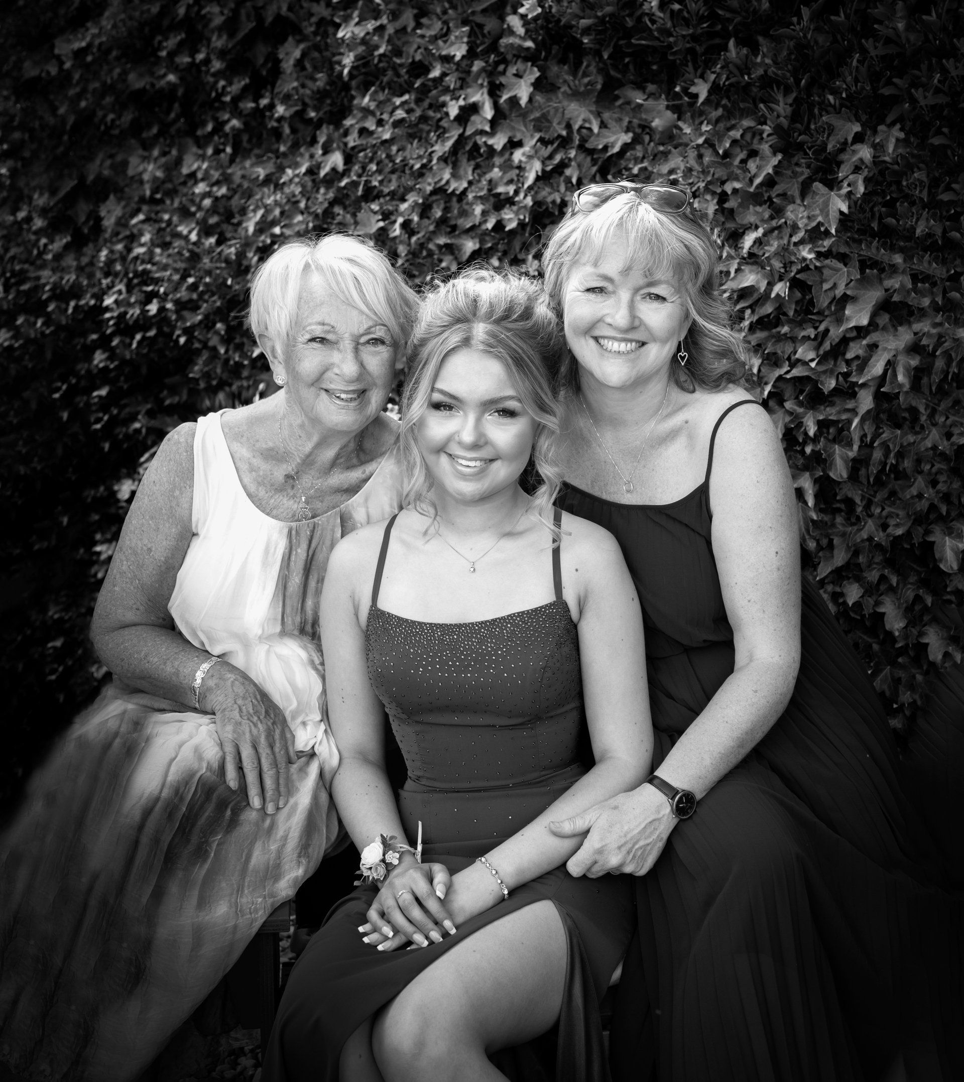 daughter, mother and grandmother sitting down for a family portrait, all smiling at the camera image in blacxk and white taken by darlington portrait photographer kate mitford
