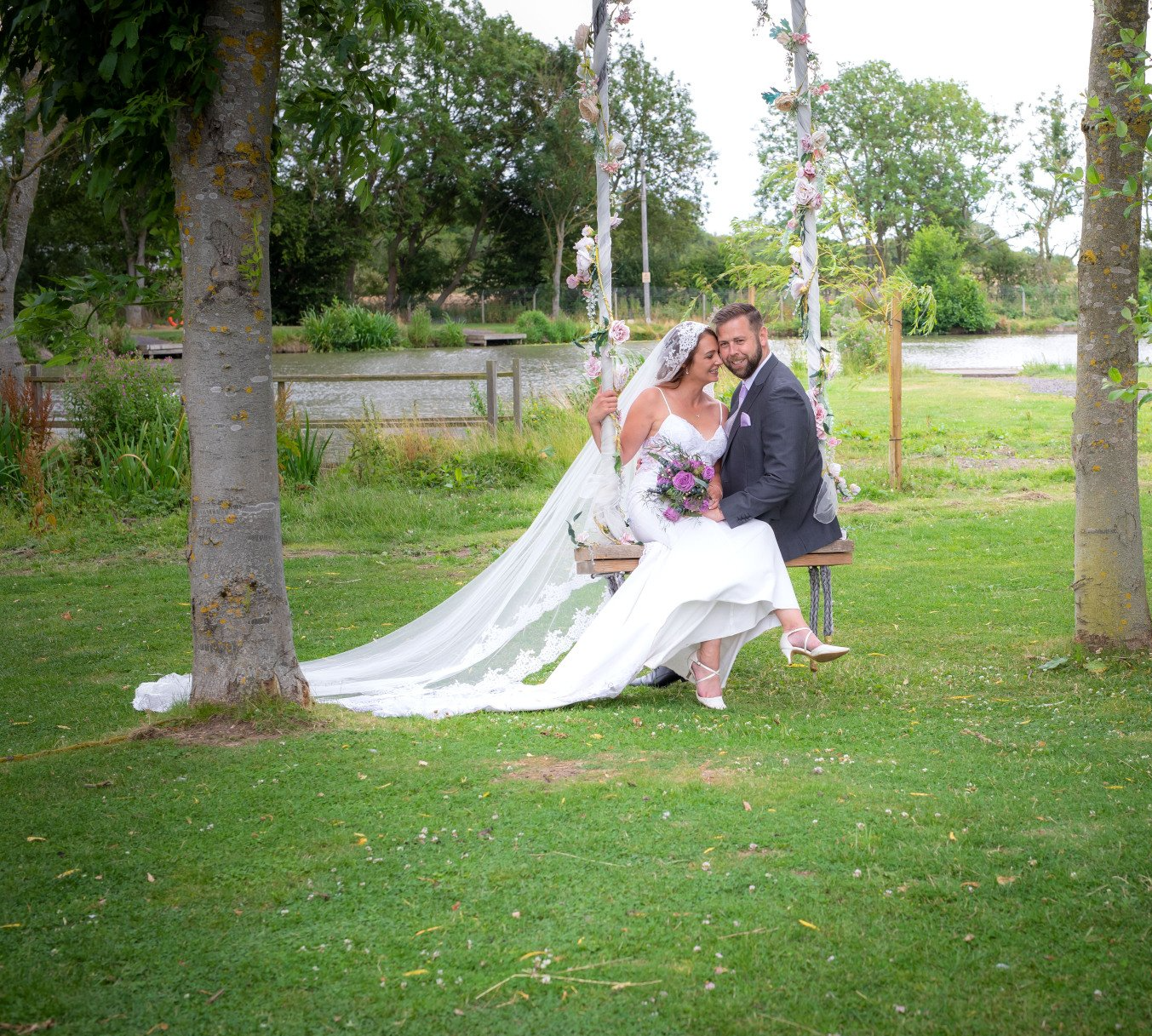 bride and groom sitting on a swing groom looking at camera and bride looking at the groom in county durham