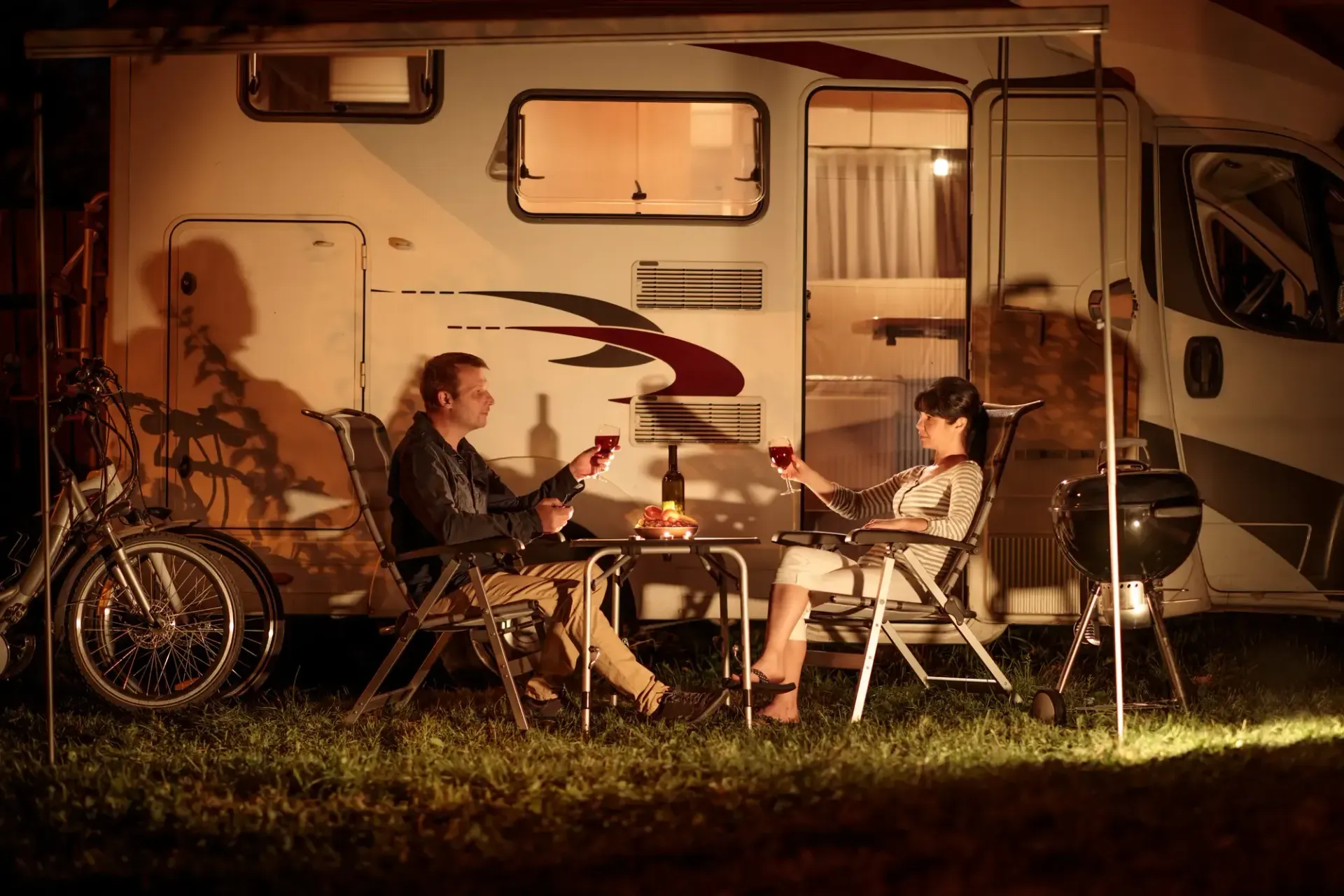 Ein Paar sitzt auf dem Campingplatz Ostseecamp Lehmberg und genießt ein Glas Rotein. Das Paar hat sich entschieden, günstig campen zu gehen, in der Vorsaison Camping. Günstige Campingplätze gibt es an der Ostsee, zum Beispiel kann man auf dem Ostseecamp Lehmberg günstig campen.