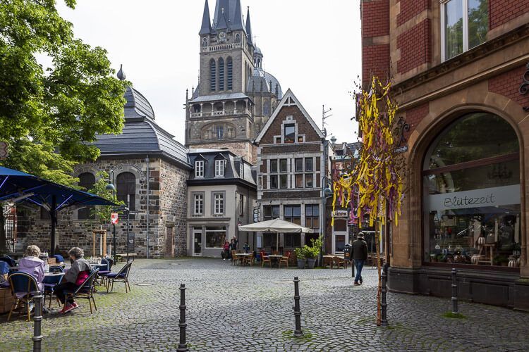 Geschichte trifft auf Moderne: der Fischmarkt. Der historische Fischmarkt in Aachen mit kleinen Fachwerkhäusern, modernen Geschäften, Cafés und dem Dom.