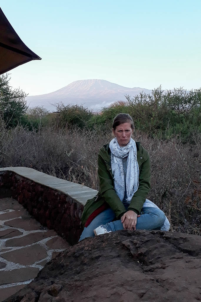 Trauriger Abschied vom Amboseli Katrin am Tag des Abschieds traurig auf der Terrasse einer Lodge. Im Hintergrund zeigt sich der Kilimandscharo in voller Pracht.