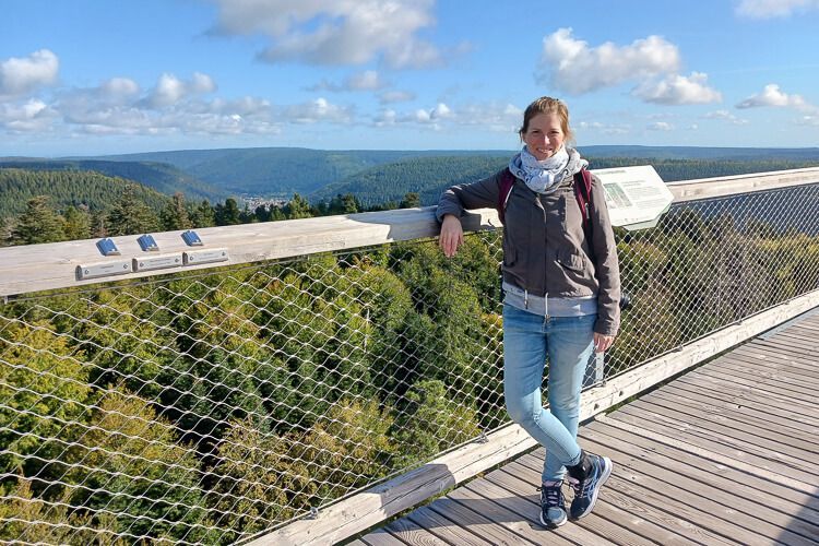 Bestes Wetter für diesen Ausblick in den Schwarzwald. Eine Frau steht auf der Aussichtsplattform des Baumwipfelpfades Bad Wildbad mit weitem Blick in den Schwarzwald.