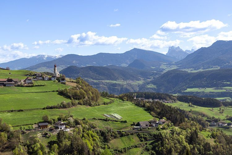 Südtirol - diese Aussicht erwartet einen, wenn man in Lengmoos die Erdpyramiden besucht. Landschaft in Südtirol mit kleinen Dörfern und einer Kirche mit charakteristischem Zwiebelturm.