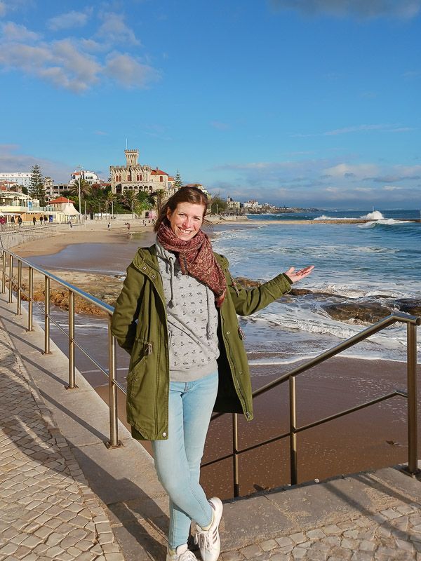 Strand bei Estoril, ich freue mich über die Sonne Eine Frau steht im Sonnenschein am Strand von Estoril und lacht in die Kamera.