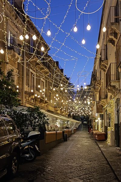 Eindrücke von Catania: Romantische Abendstimmung Nebenstraße in Catania bei Abenddämmerung. Die Straße ist erleuchtet von unzähligen Lichterketten.