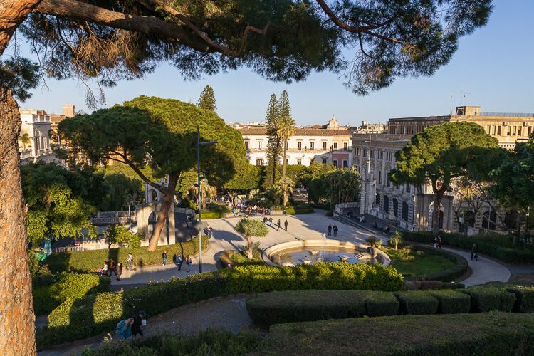 Ein Ort der Ruhe im trubeligen Catania Giardino Bellini in Catania mit üppigen Pinien und Blick auf den Vorplatz.