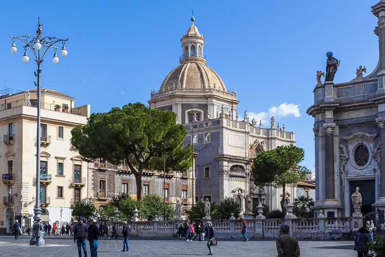 Tolle Eindrücke von Catania: die Piazza del Duomo mit der Chiesa della Badia di Sant’Agata Die Piazza del Duomo in Catania mit der Chiesa della Badia di Sant’Agata und großen Pinienbäumen.