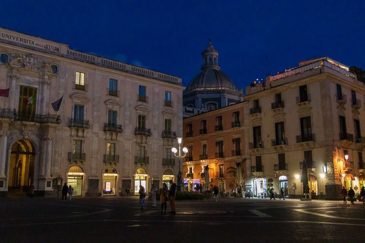 Die Piazza Università in Catania sanft beleuchtet am Abend. Die Piazza Università in Catania sanft beleuchtet am Abend. Im Hintergrund ist die Kuppel der Chiesa della Badia di Sant’Agata.