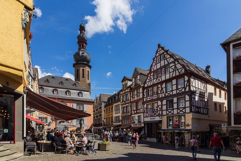 Bei schönem Wetter ist am Wochenende am Marktplatz in Cochem einiges los Altstadt von Cochem mit Marktplatz, hinter den Fachwerkhäusern ragt ein Kirchturm hervor.