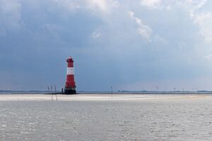 Im Jadebusen in der Nordsee steht der Leuchtturm Arngast. Es bilden sich durch dunkle Wolken und die noch scheinende Sonne beeindruckende Kontraste.