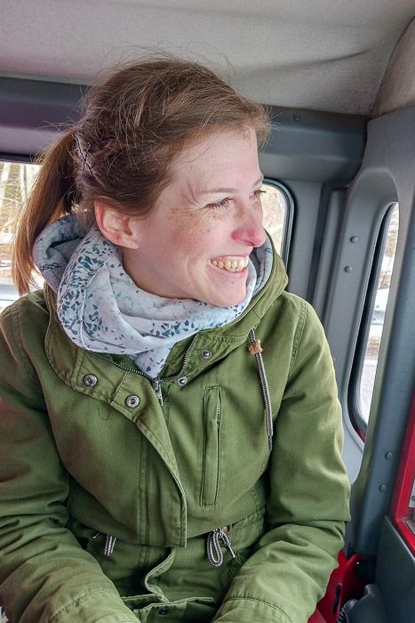 Die Laune im Jeep ist gut Eine Frau sitzt lachend in einem Jeep und blickt zum Fenster hinaus.