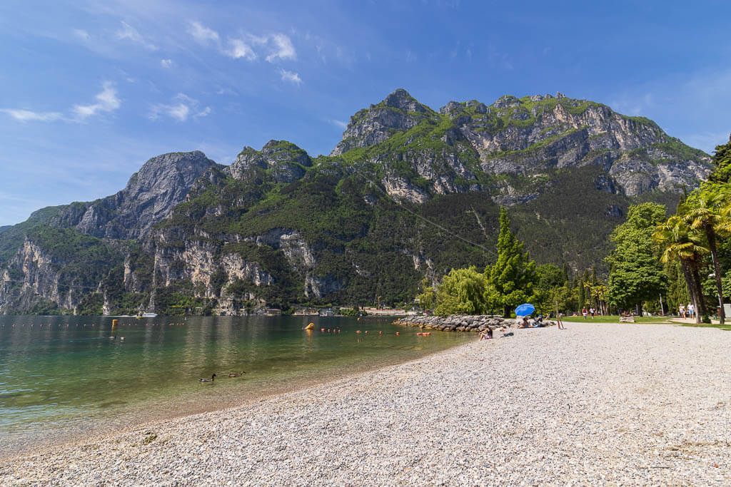 Ufer des Gardasees, im Hintergrund thront eine Bergwand.