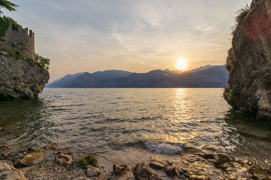 Premiumplatz für einen Sonnenuntergang am Gardasee: Spiaggia di Posterna in Malcesine. In der Bucht Spiaggia di Posterna in Malcesine bei Sonnenuntergang.