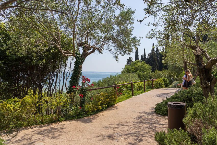 Unbedingt sehenswert: Park in Sirmione Park in Sirmione: Ein Weg führt oberhalb des Gardasees entlang und bietet einen Ausblick auf türkises Wasser.