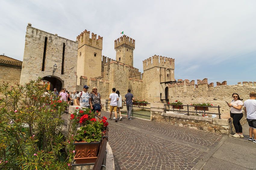 Blick auf die Scaligerburg und das Stadttor in Sirmione mit Blumen im Vordergrund.