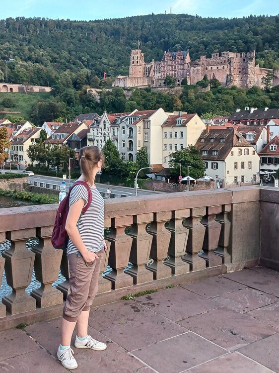 Sightseeing in Heidelberg Eine Frau steht auf der Alten Brücke in Heidelberg und blickt auf das Schloss.