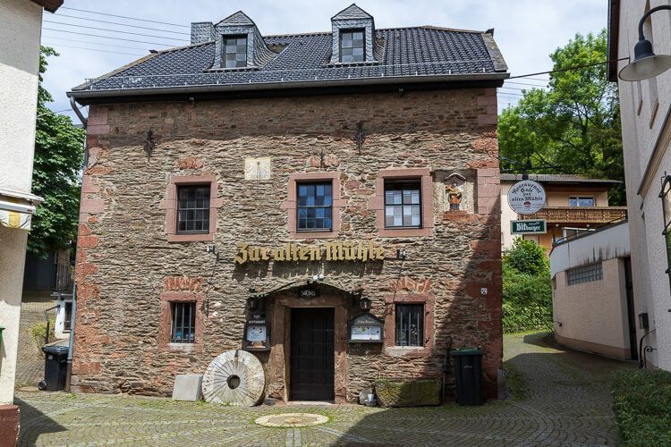 Restaurant Zur Alten Mühle in Heimbach in einem historischen Gebäude mit einem Mühlstein am Eingang.